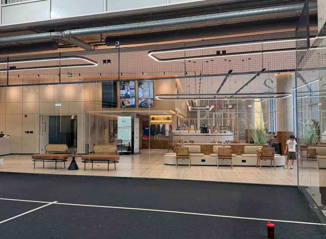 An indoor court at Padel Center, looking through the glass to the lounge